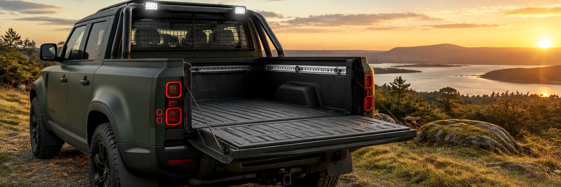 Rear view of a matte forest-green NEW Defender UTE concept with open damped tailgate and tray bed on www.defender-accessories.com